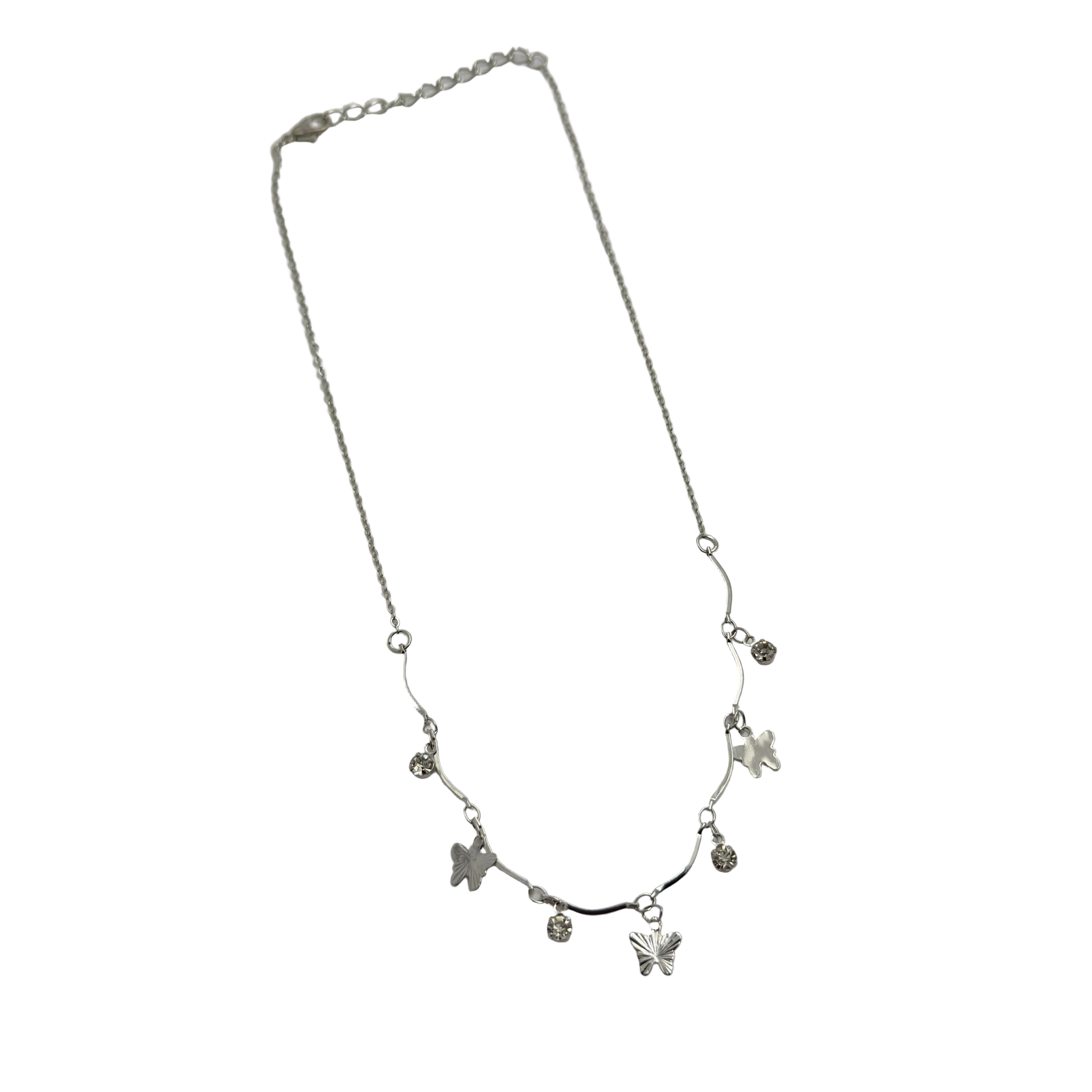 Polished silver butterfly charm necklace with clear crystal accents, worn on model at the beach