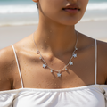 Polished silver butterfly charm necklace with clear crystal accents, worn on model at the beach