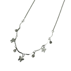 Polished silver butterfly charm necklace with wavy bar and crystal accents, close-up detail on black background