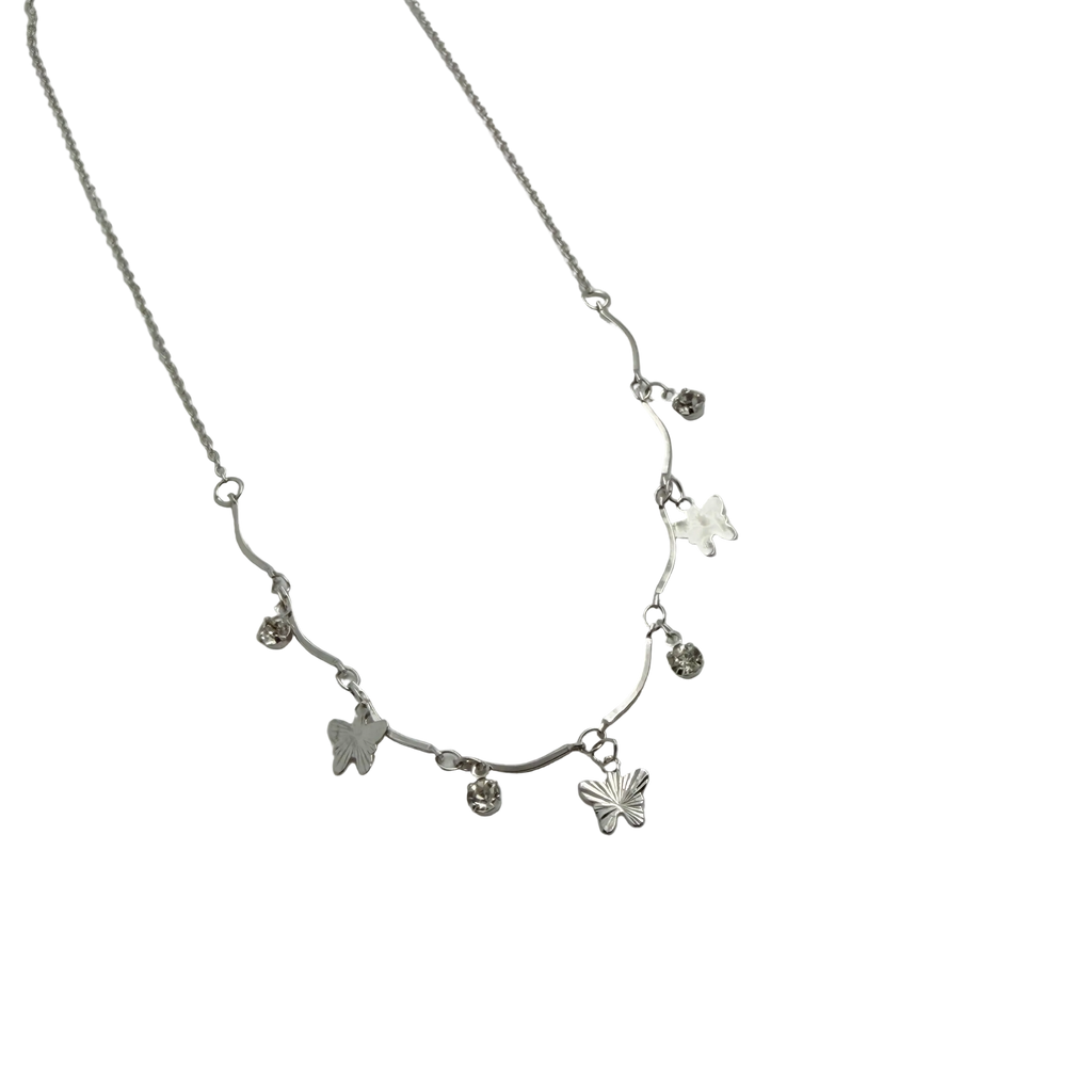 Polished silver butterfly charm necklace with wavy bar and crystal accents, close-up flat-lay detail