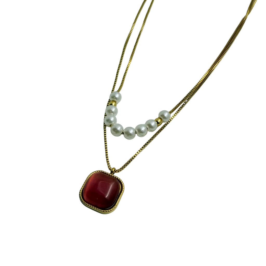 Gold-tone layered necklace with pearls and carnelian pendant, worn on neck at the beach