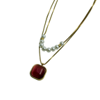 Gold-tone layered necklace with pearls and carnelian pendant, worn on neck at the beach