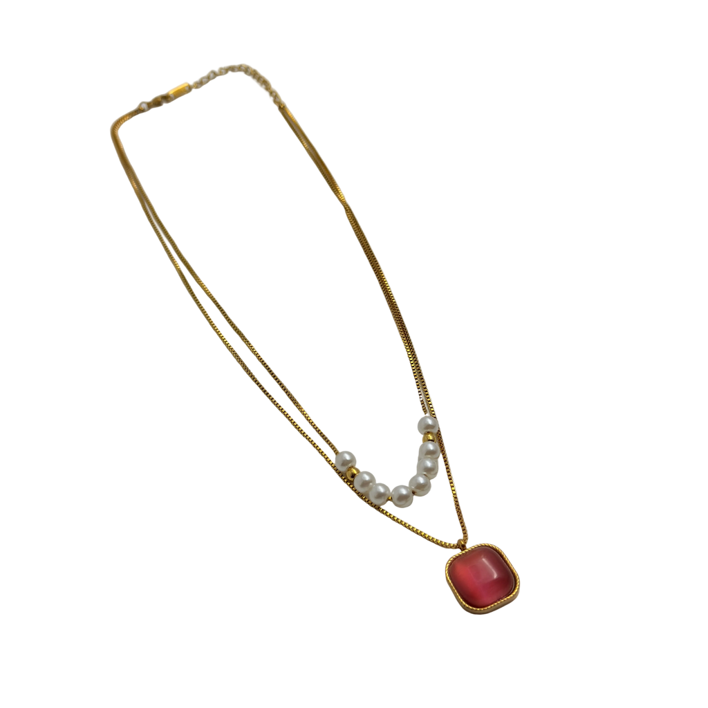 Gold-tone layered necklace with pearls and carnelian pendant, full flat-lay view on black background