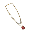 Gold-tone layered necklace with pearls and carnelian pendant, full flat-lay view on black background