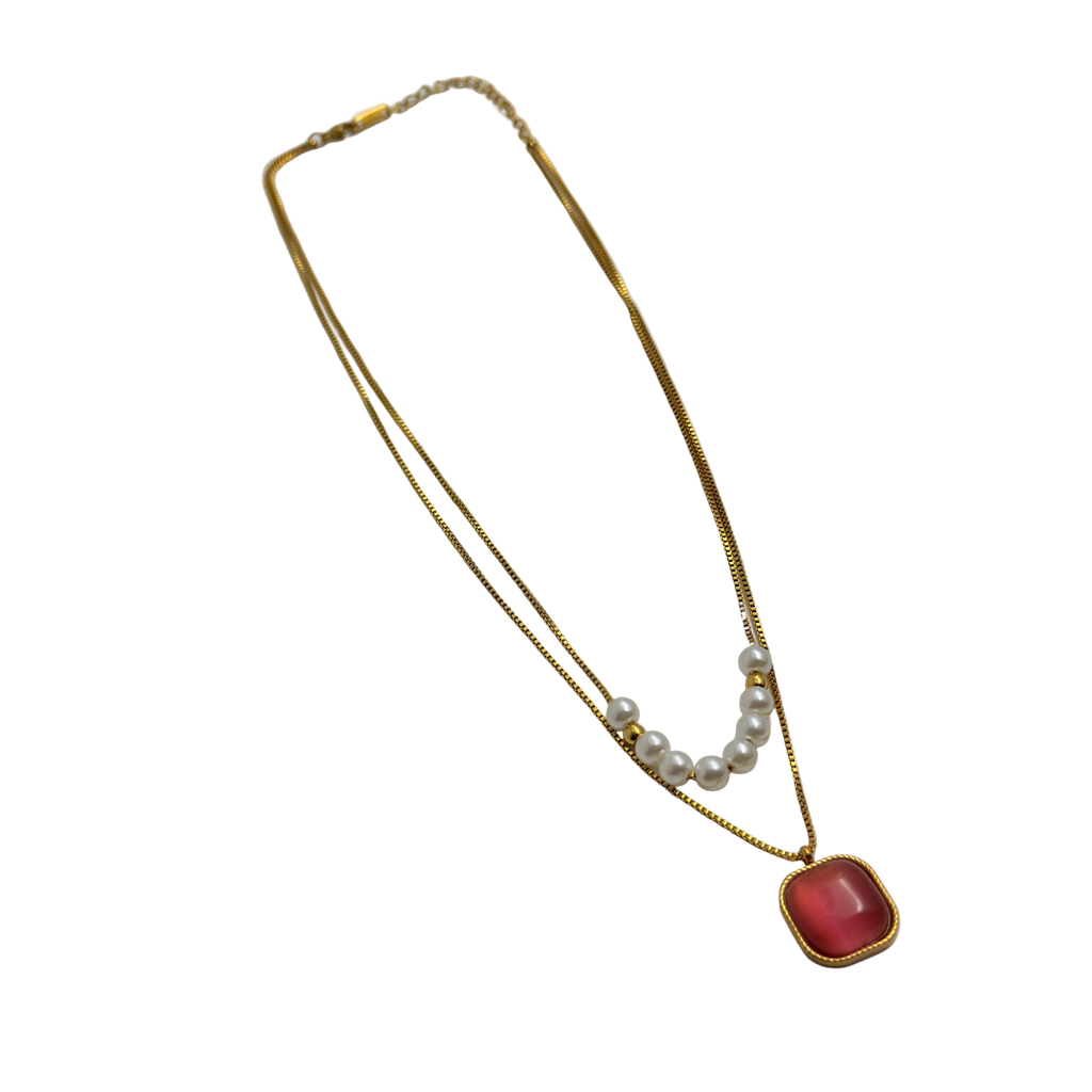 Gold-tone layered necklace with pearls and carnelian pendant, full flat-lay view on black background