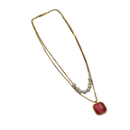 Gold-tone layered necklace with pearls and carnelian pendant, full flat-lay view on black background