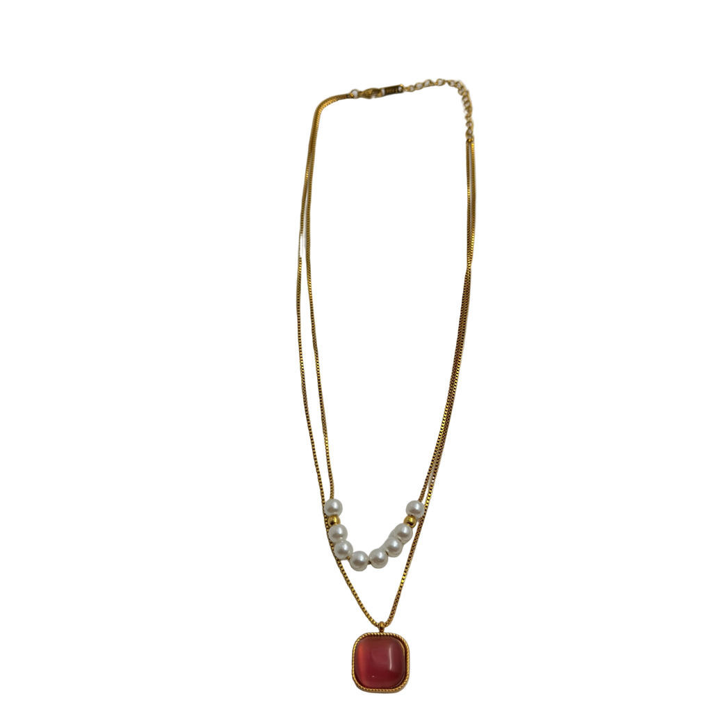 Gold-tone necklace pendant close-up showing cushion-cut carnelian cabochon and pearl accents