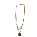 Gold-tone necklace pendant close-up showing cushion-cut carnelian cabochon and pearl accents