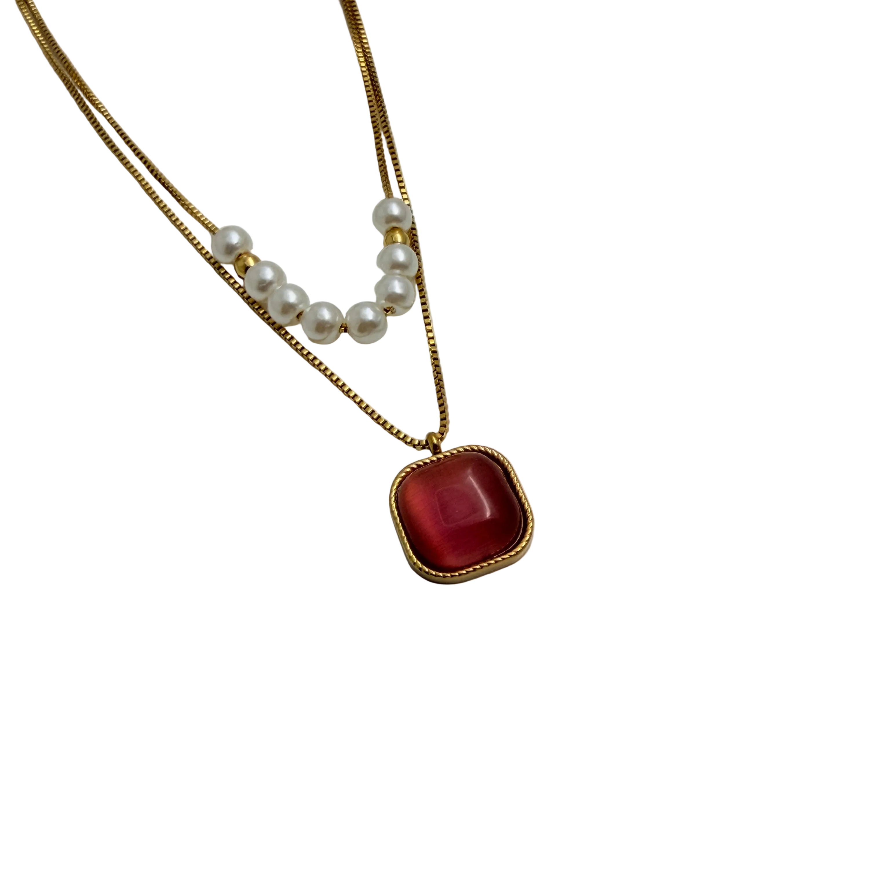 Gold-tone layered necklace with pearls and carnelian pendant, angled flat-lay view on black background