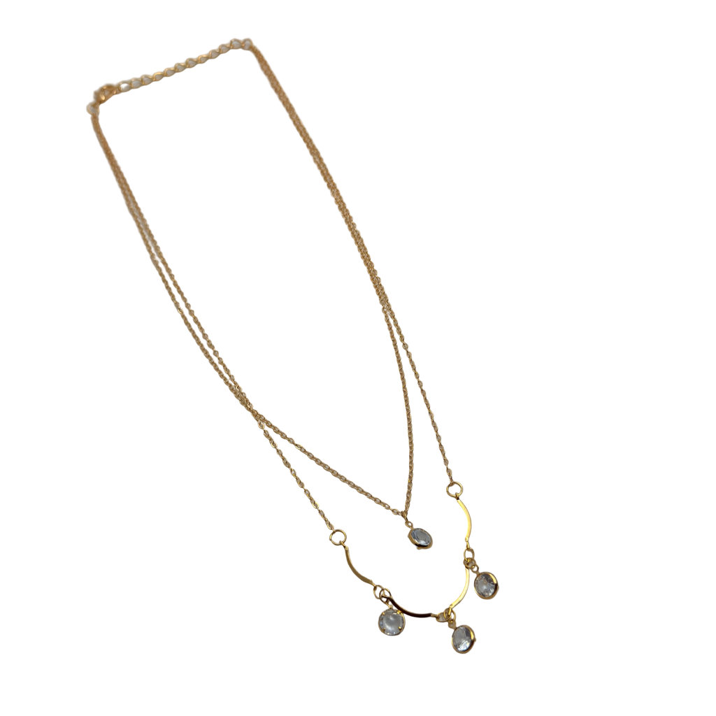 Gold-tone double-layer necklace with clear crystal charms, flat lay showing full chain length