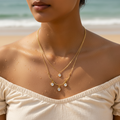 Gold-tone double-layer necklace with clear crystal charms, flat lay showing full chain length