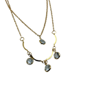 Gold-tone double-layer necklace with wavy bar and four clear crystal charms, flat lay close-up