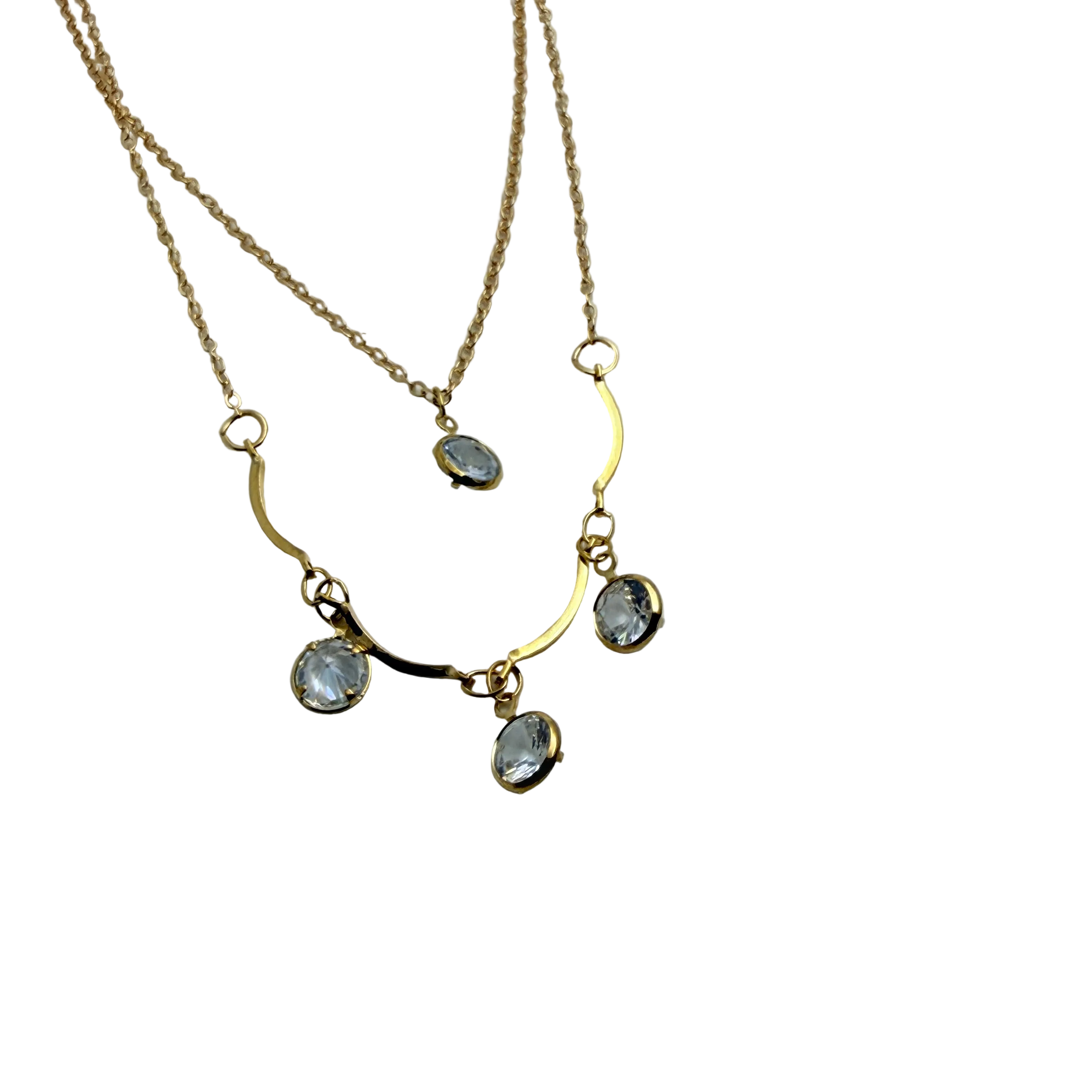 Gold-tone double-layer necklace with wavy bar and four clear crystal charms, flat lay close-up