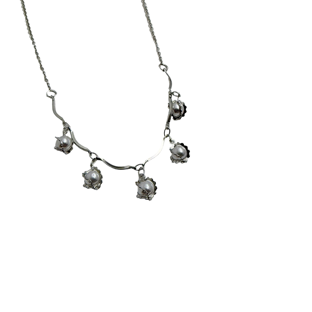 Silver-tone pearl charm necklace with wavy collar bar, worn on neck at the beach