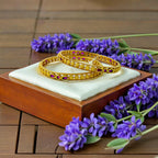 Gold studded bangles pair with pink stones and floral filigree, flat-lay with lavender flowers