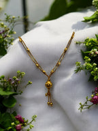 Gold beaded chain necklace with textured bead pendant, worn on a model with a festive saree