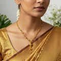 Gold beaded chain necklace with textured bead pendant, worn on a model with a festive saree