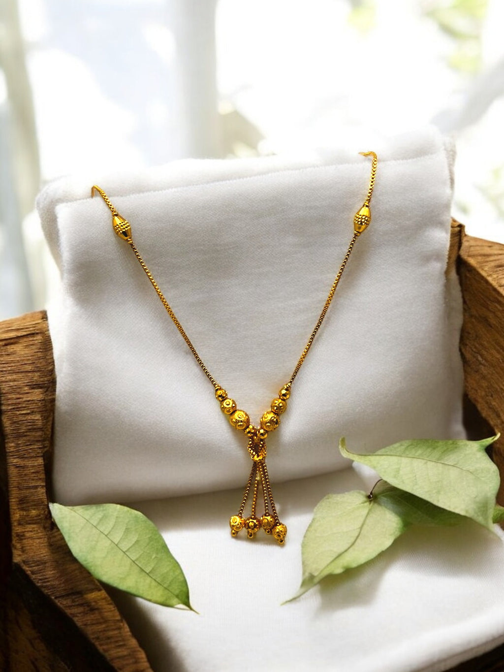 Gold-plated beaded tassel necklace with textured gold bead drops, worn on model with blue saree