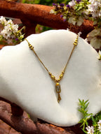 Gold necklace with textured bead clusters and a sparkling tassel pendant, worn on model with a saree