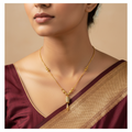 Gold necklace with textured bead clusters and a sparkling tassel pendant, worn on model with a saree