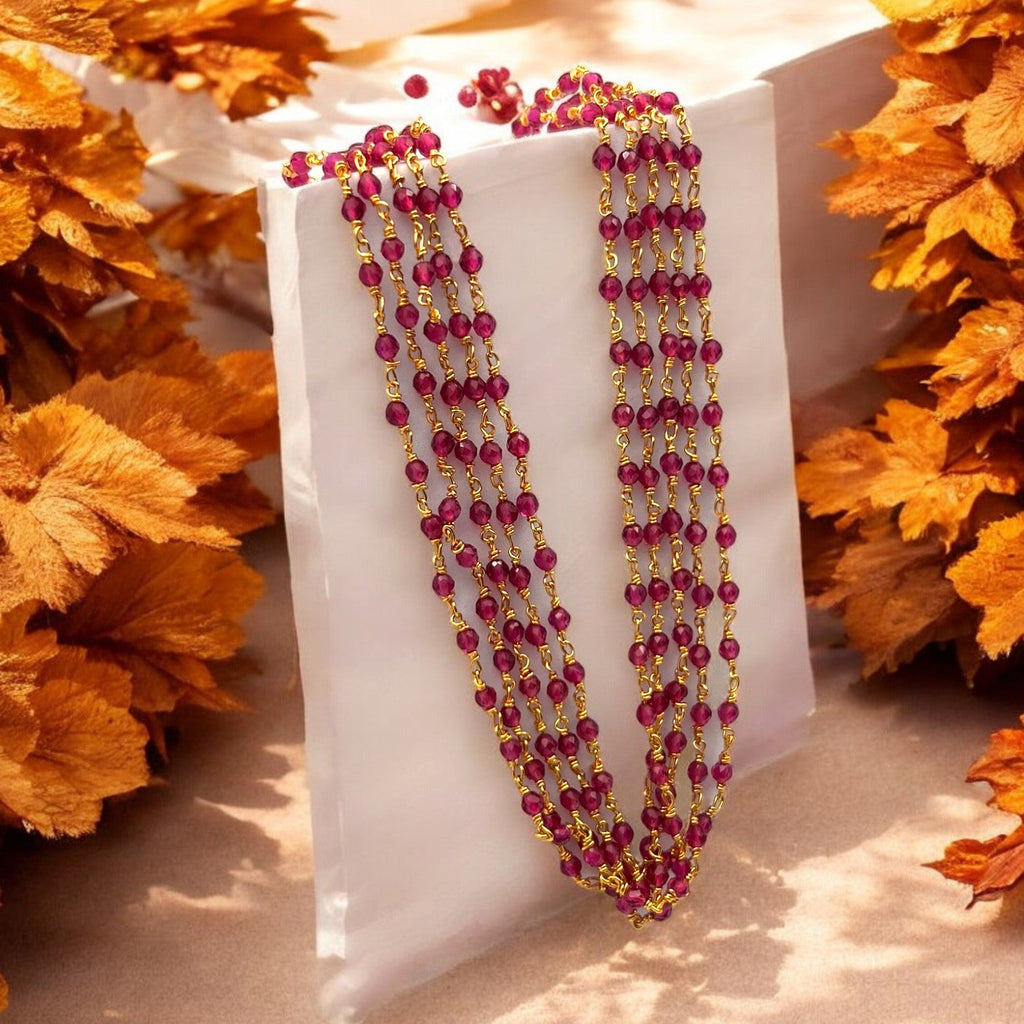 Gold-plated layered necklace with ruby-red beads, worn on model over a maroon and gold saree