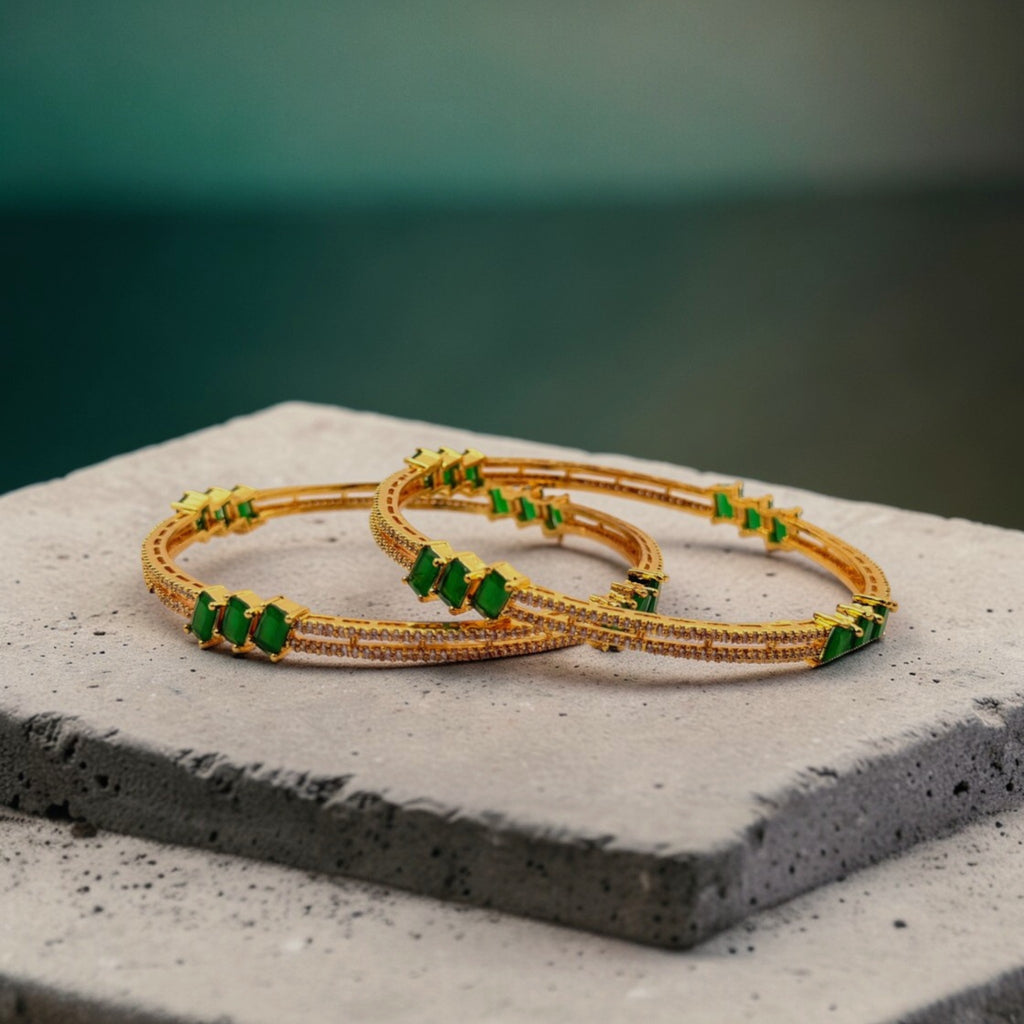 Gold bangle set with emerald-green stones and pave crystal band, worn on wrist by a pool