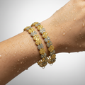 Gold openwork floral bangle set worn on wrist, showing both bangles stacked with rhodium accent detailing