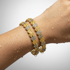 Gold openwork floral bangle set worn on wrist, showing both bangles stacked with rhodium accent detailing