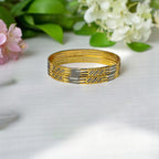 Gold two-tone bangle set with CZ-studded panels, worn on a wet wrist poolside