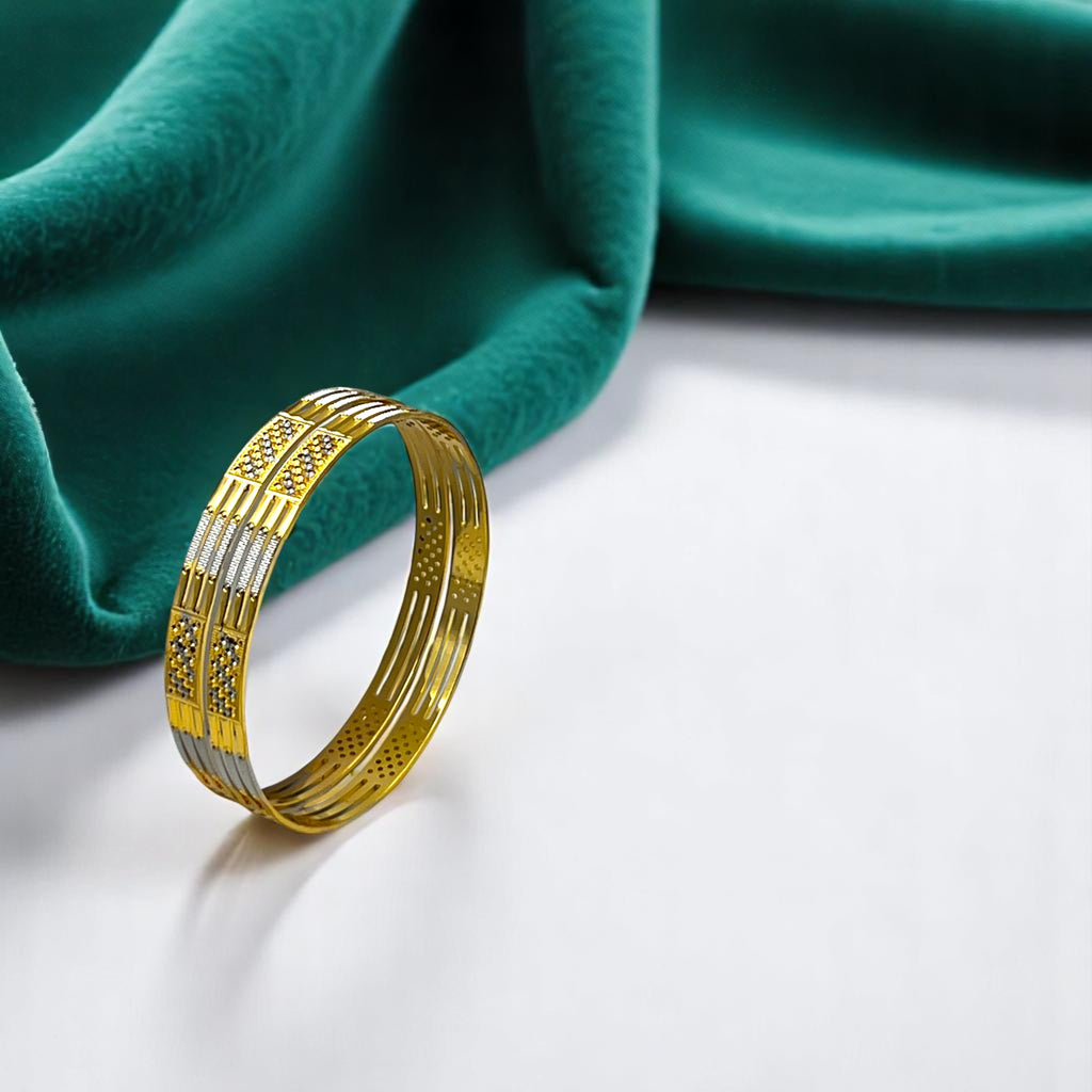 Gold two-tone bangle set with silver-tone accents and CZ panels, flat-lay on green fabric