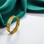 Gold two-tone bangle set with silver-tone accents and CZ panels, flat-lay on green fabric