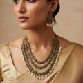 Antique gold necklace set with layered floral stonework and pearl drops, worn by a model with matching earrings