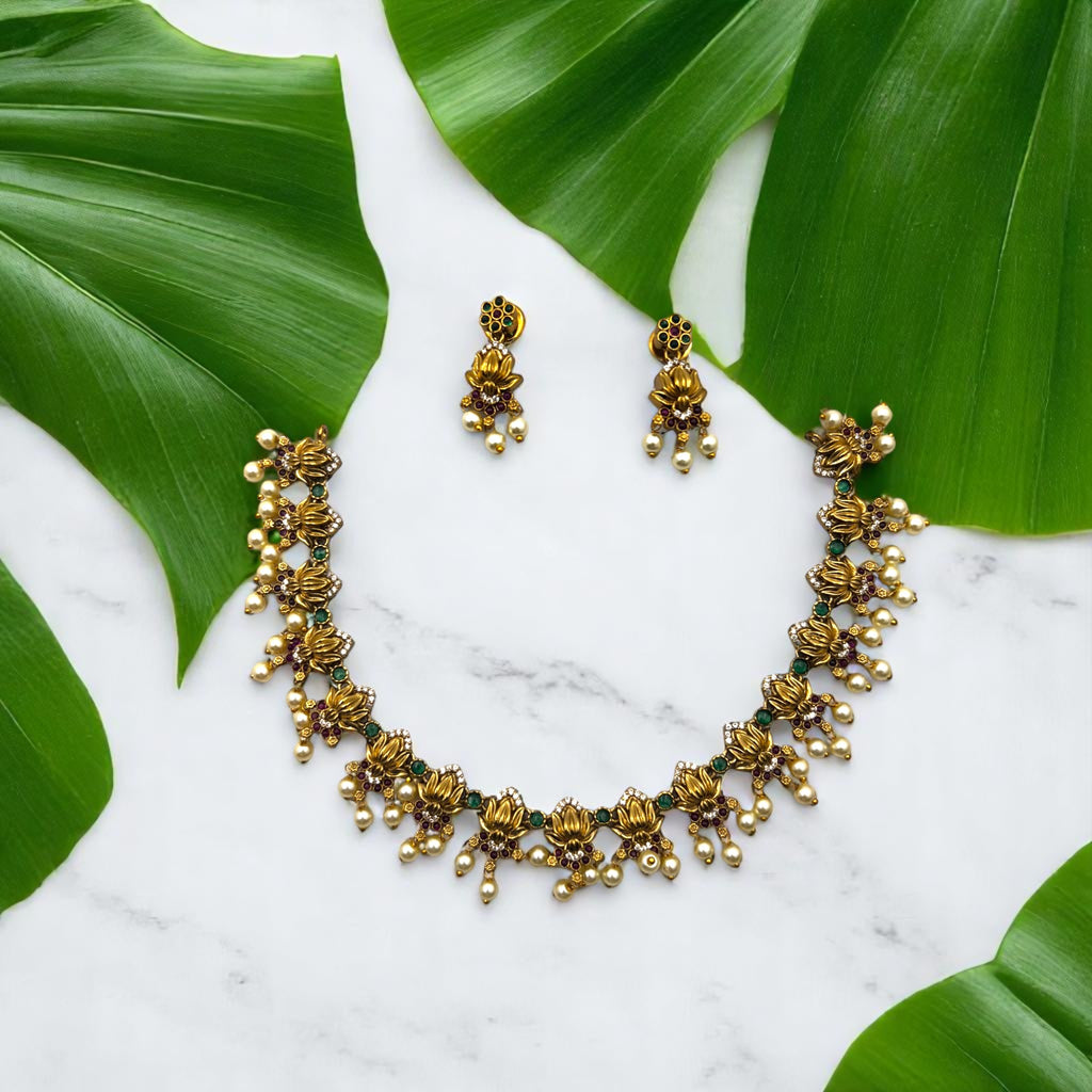 Antique gold-toned floral necklace and earrings set with pearl tassels, worn on model at neck and ear