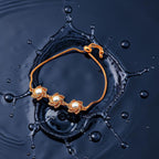 Gold-toned pearl bracelet with floral CZ motifs and slider chain, worn on wrist with water droplets