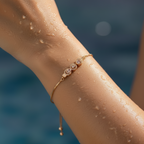 Rose gold-toned adjustable chain bracelet with triple halo stone motif, flat-lay on dark water