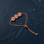 Rose gold trio concentric-circle crystal bracelet with adjustable slider chain, flat-lay on dark background