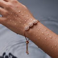 Rose gold trio concentric-circle crystal bracelet with adjustable slider chain, shown on wrist with water droplets