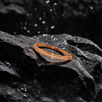 Rose gold bangle bracelet with pavé crystal line and pearl accent, flat-lay on dark stone