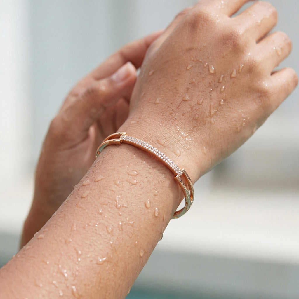 Rose gold crystal-studded bangle bracelet with pave bar, worn on a wet wrist