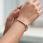 Rose gold crystal-studded bangle bracelet with pave bar, worn on a wet wrist