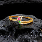 Gold bracelet with gemstones on a black textured surface