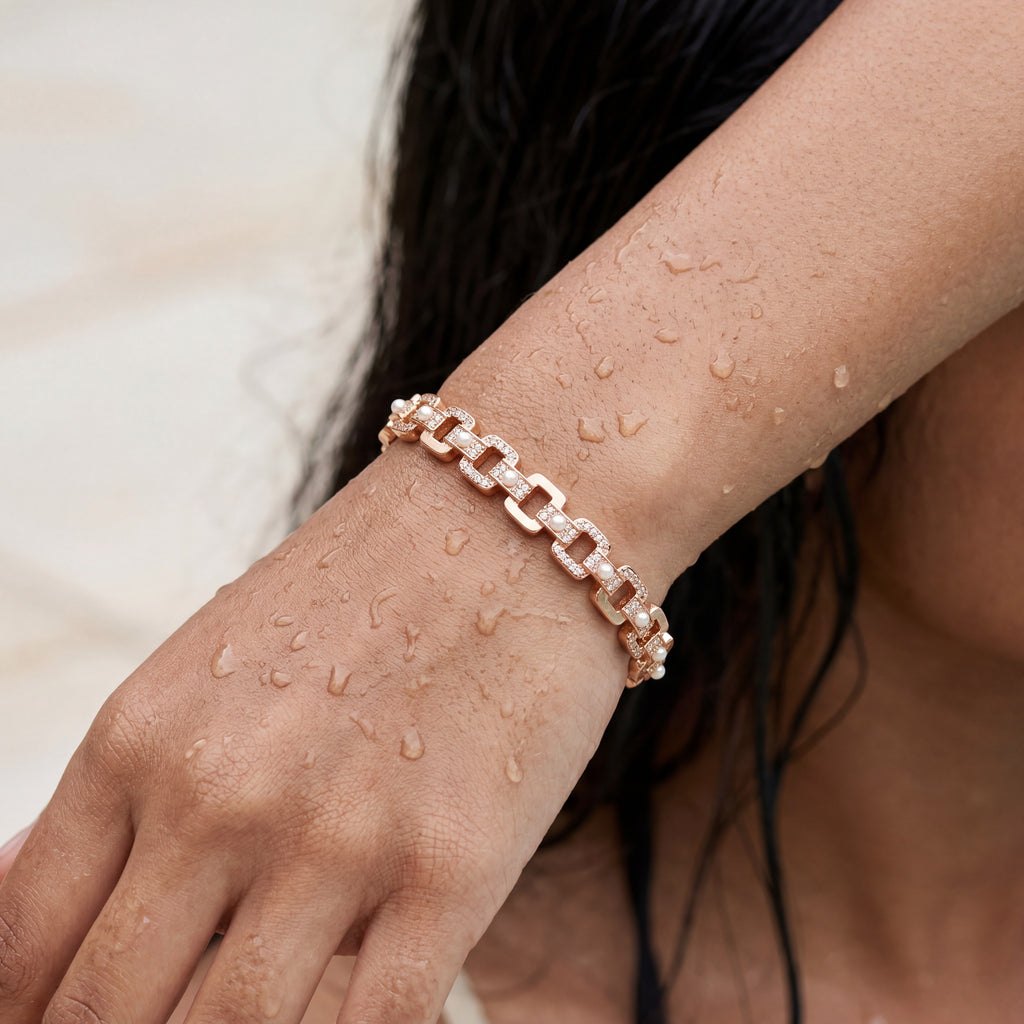 Rose gold link bracelet with crystal pave and pearl accents, worn on model's wrist close-up