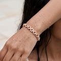 Rose gold link bracelet with crystal pave and pearl accents, worn on model's wrist close-up
