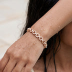 Rose gold link bracelet with crystal pave and pearl accents, worn on model's wrist close-up