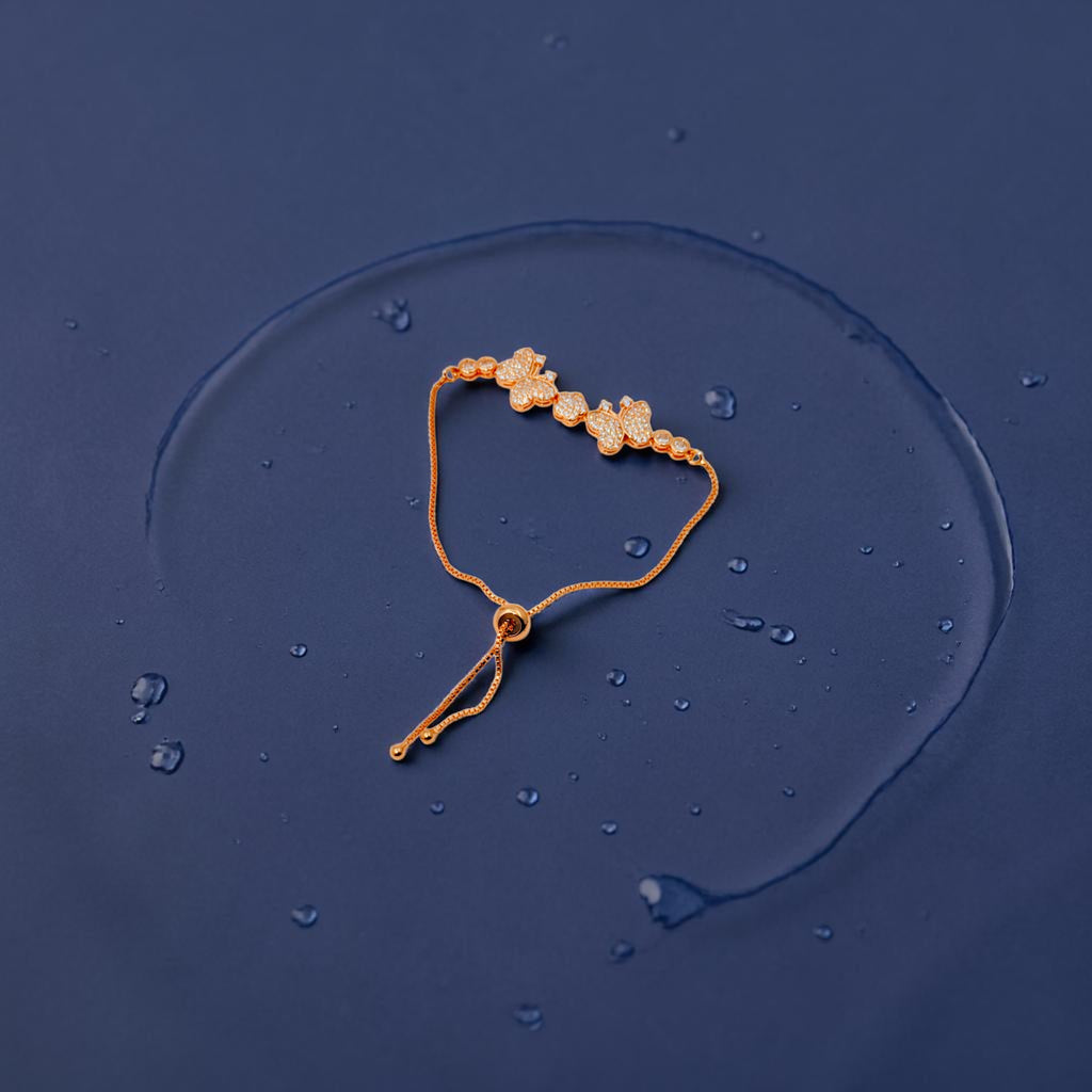 Rose gold butterfly bracelet with CZ stones and pearl accents, flat-lay shot on dark surface with water droplets