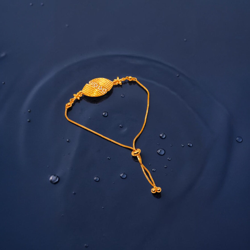 Gold leaf-shaped bracelet with crystal accents and adjustable slider, worn on wrist with water droplets