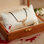 Rose gold-tone mangalsutra with black beads and CZ infinity curve pendant, flat-lay in jewellery box