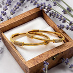 Gold twisted cuff bangles with crystal accent bar, worn stacked on wrist