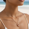 Rose gold butterfly crystal pendant necklace with center CZ stone, worn on neck at the beach showing waterproof finish