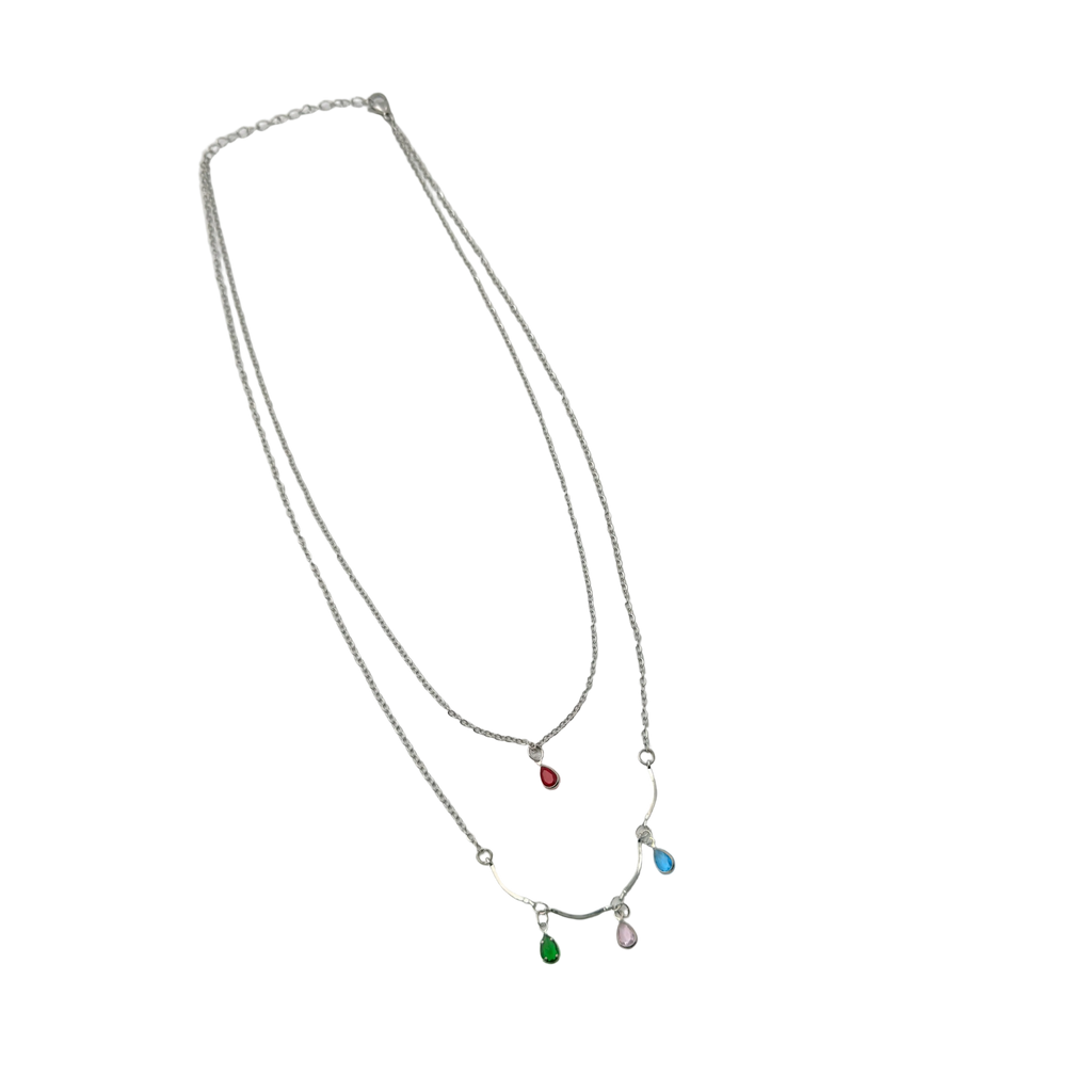 Silver-tone layered necklace with pastel teardrop crystal charms, worn on model at beach, close-up on neck